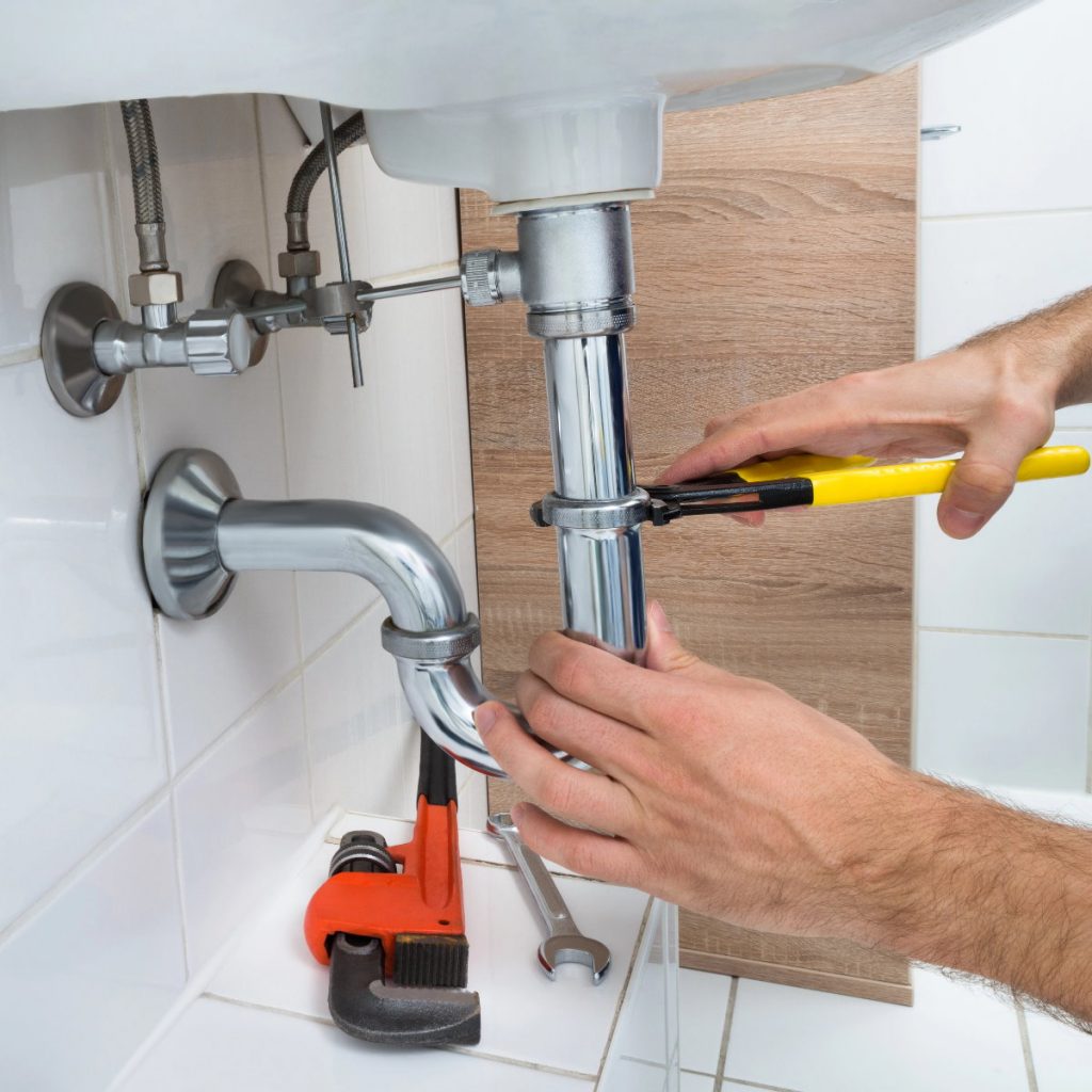 Das Bild zeigt Hände die ein Abfluss reparieren
